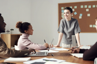 Woman Wearing Gray Shirt Leading a Meeting